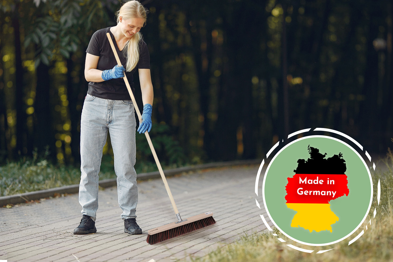 Frau mit Besen auf Gehweg. Badge "Made in Germany" in der Ecke